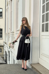 a lady in a black vest dress with a belt